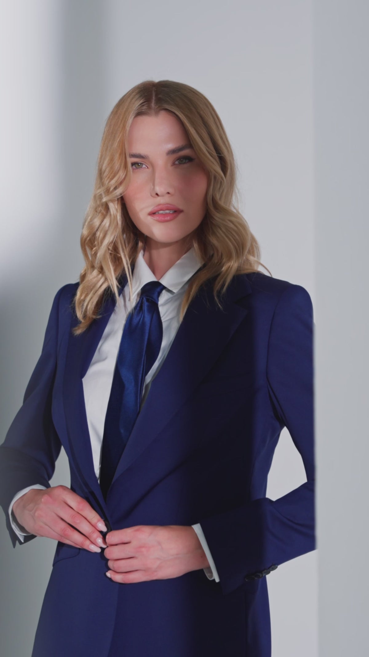 Women’s navy jacket with a white shirt and dark tie