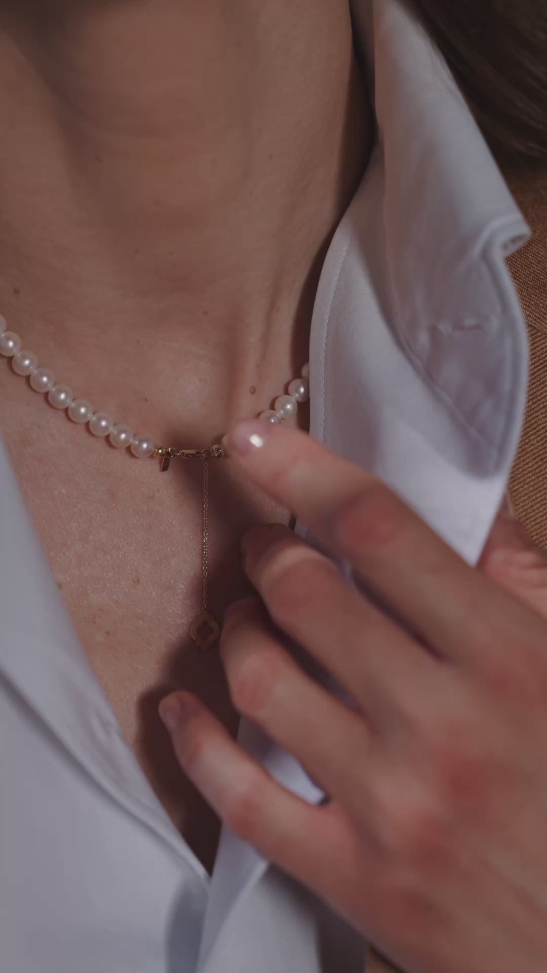 An open-neck white shirt and a delicate necklace in a Consiglieri ensemble