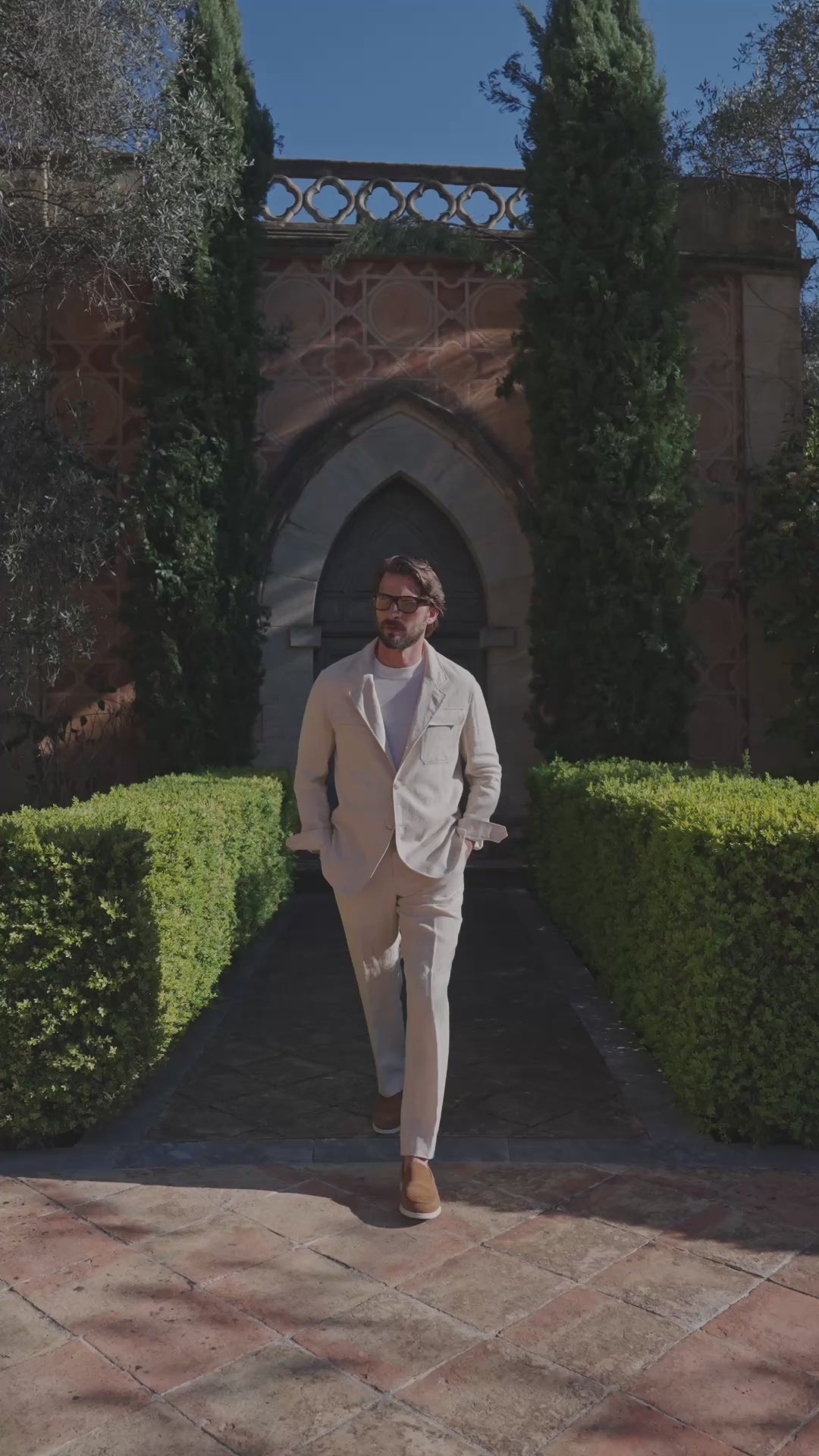 Pale beige Consiglieri Cap-Ferrat suit beneath an arch surrounded by greenery