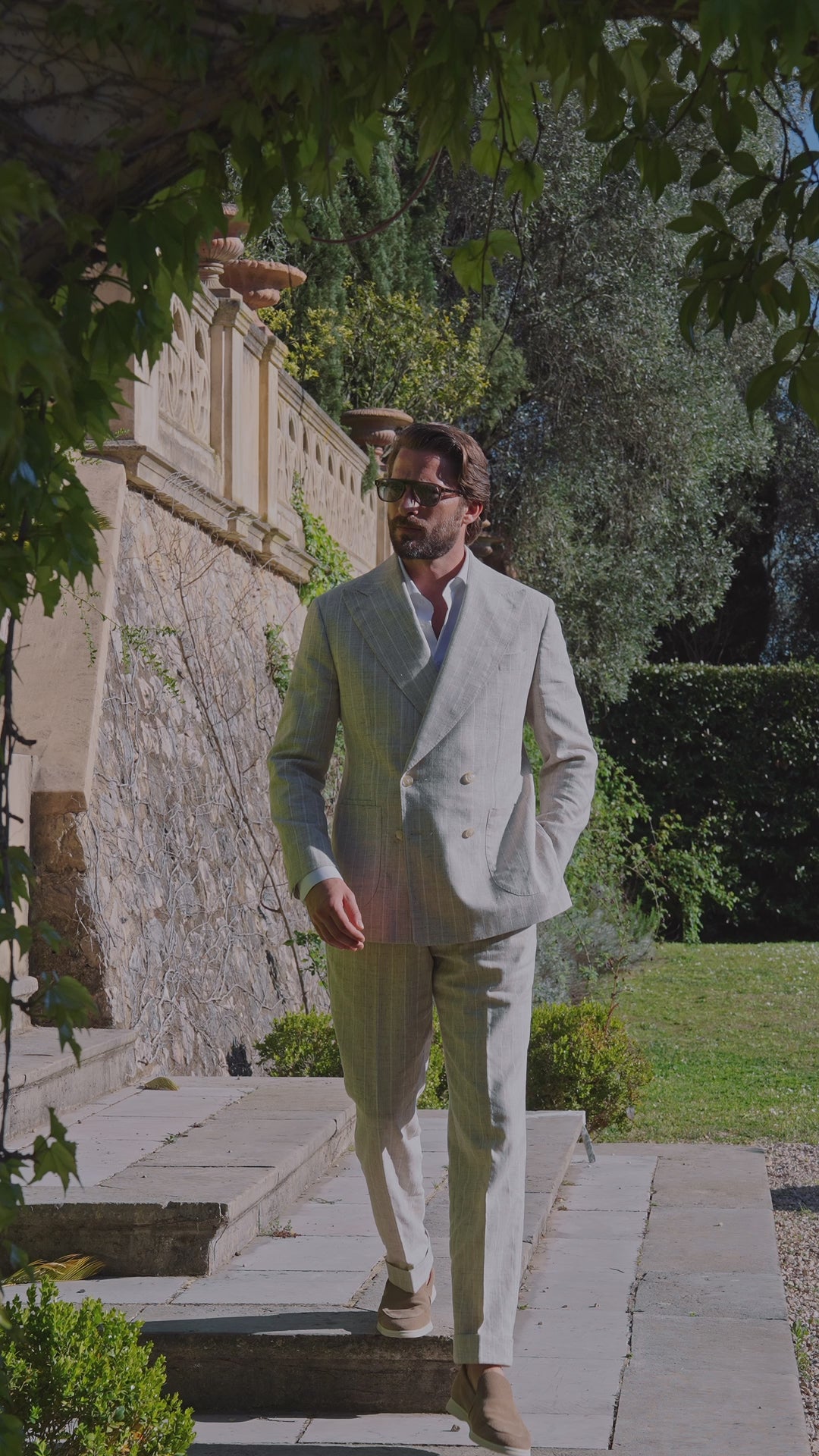 Men’s light grey suit worn on steps in a garden