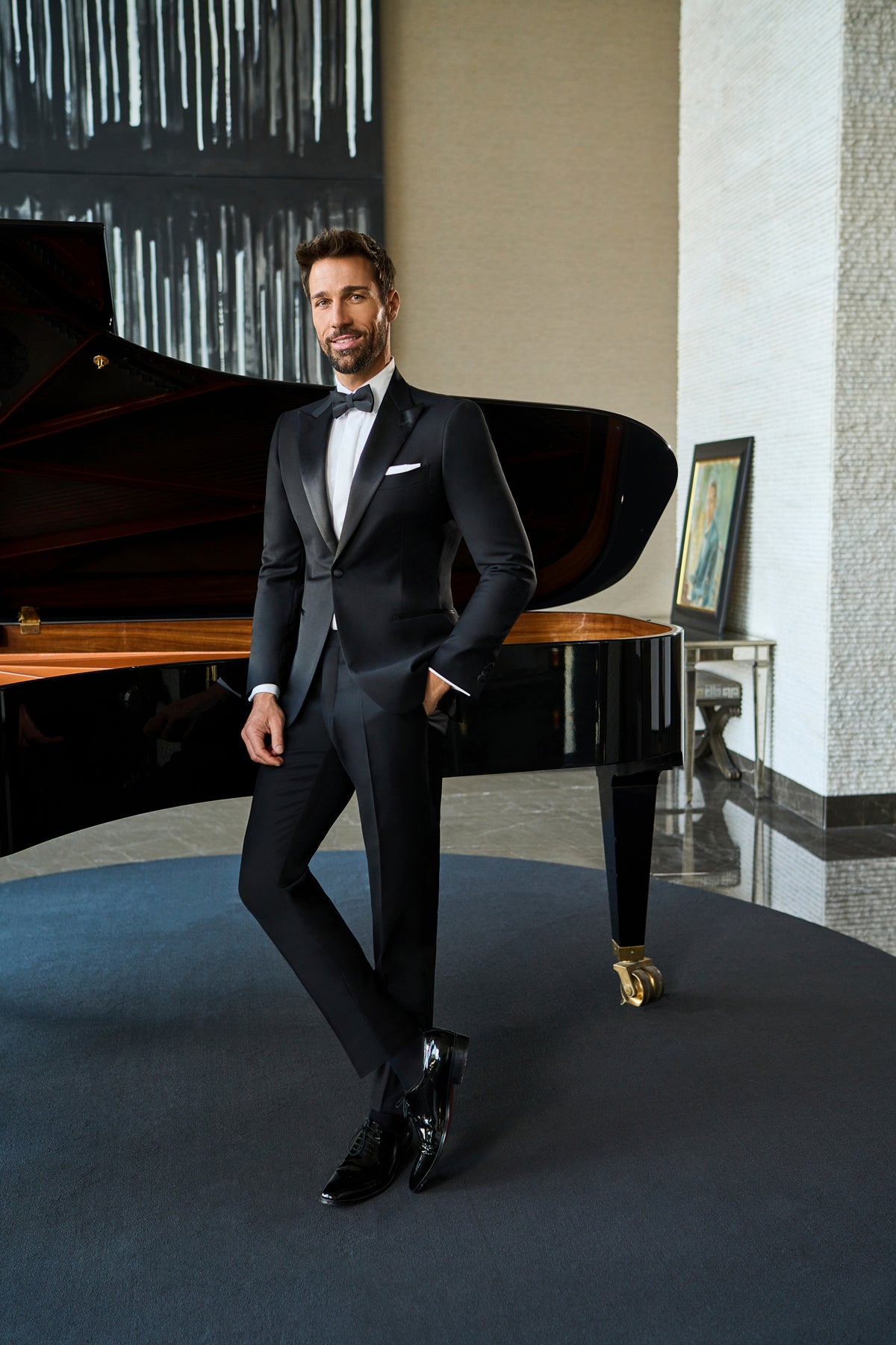 Consiglieri: black shawl-collar tuxedo with a white shirt and bow tie beside a piano