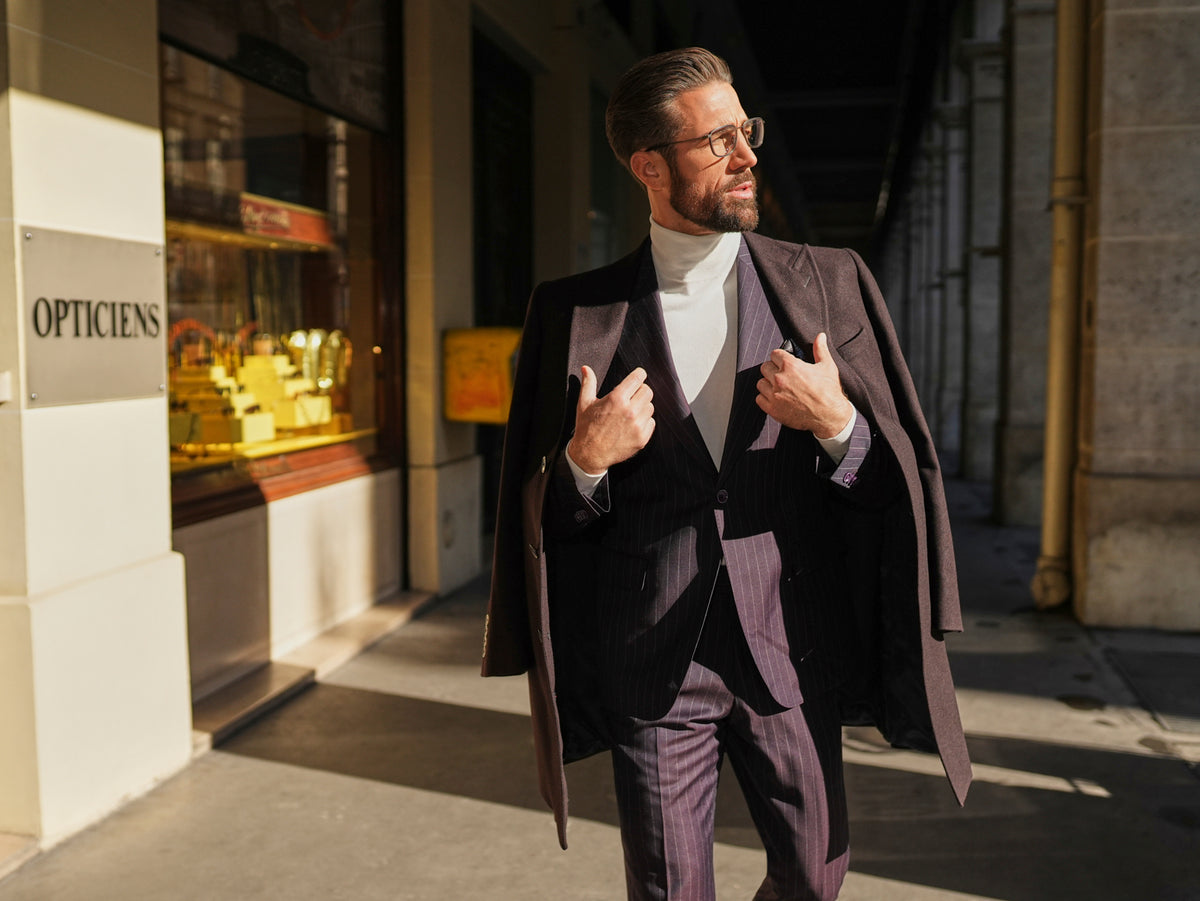 Consiglieri St Moritz: dark overcoat draped over a fine-striped suit