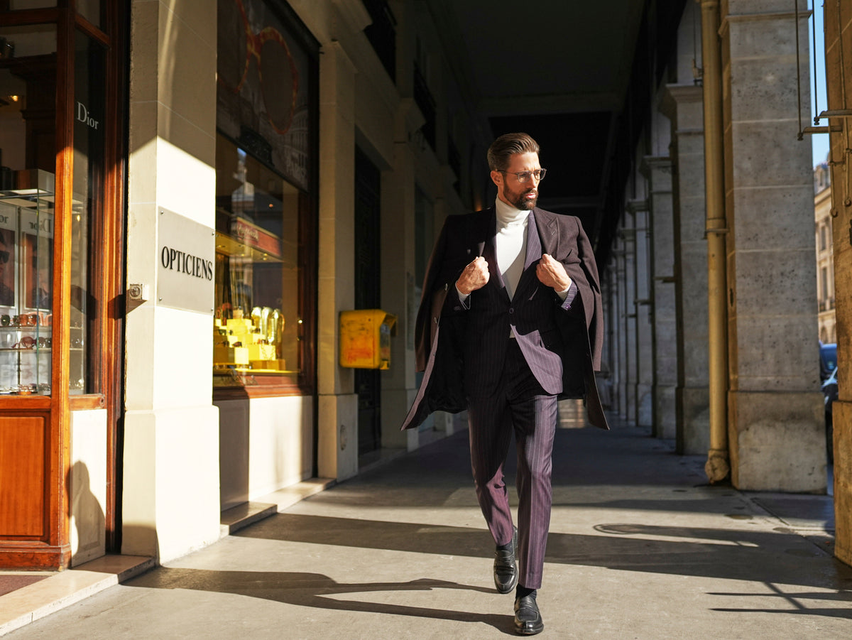 Consiglieri St Moritz: dark overcoat draped over a fine-striped suit