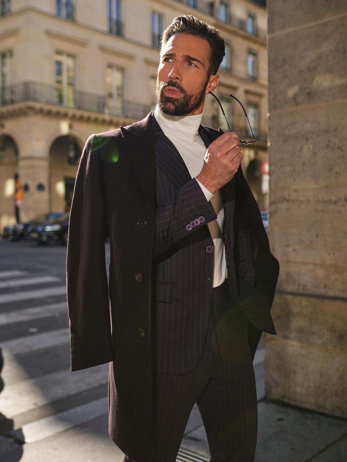 Consiglieri St Moritz: dark overcoat draped over a fine-striped suit