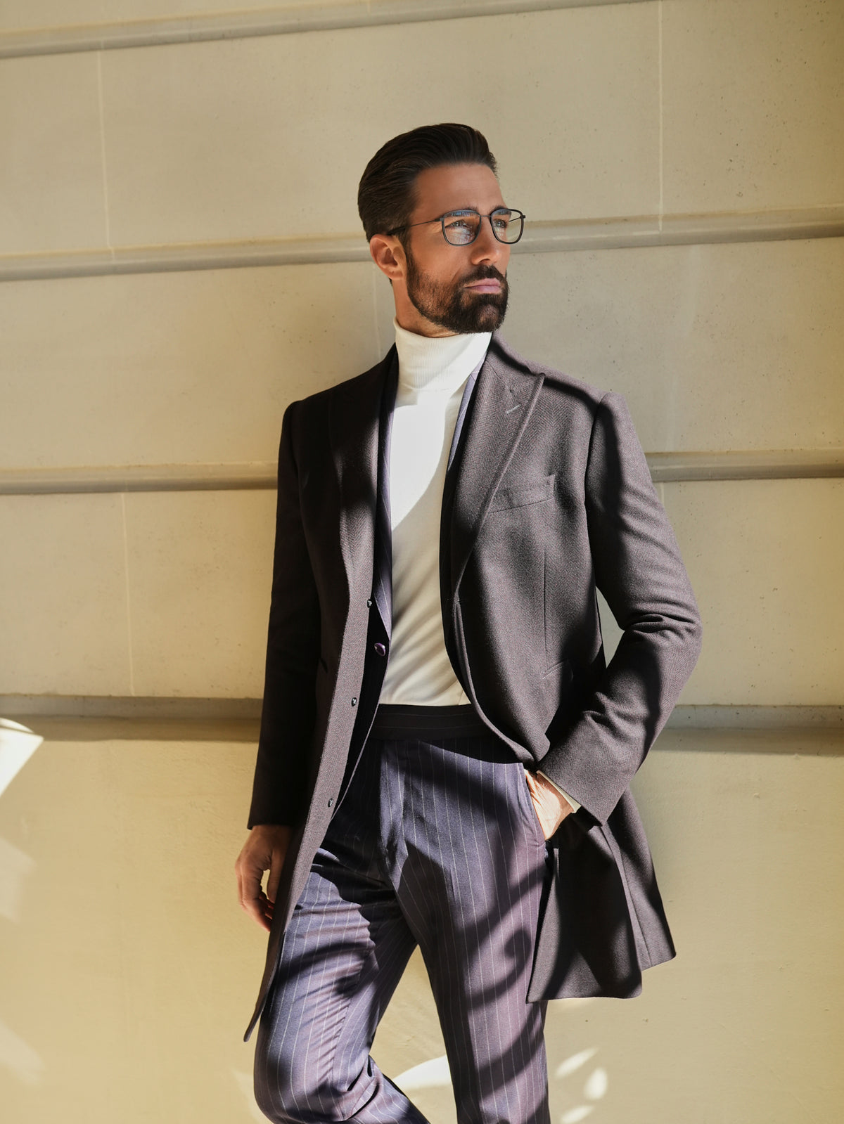 Consiglieri St Moritz: dark overcoat draped over a fine-striped suit