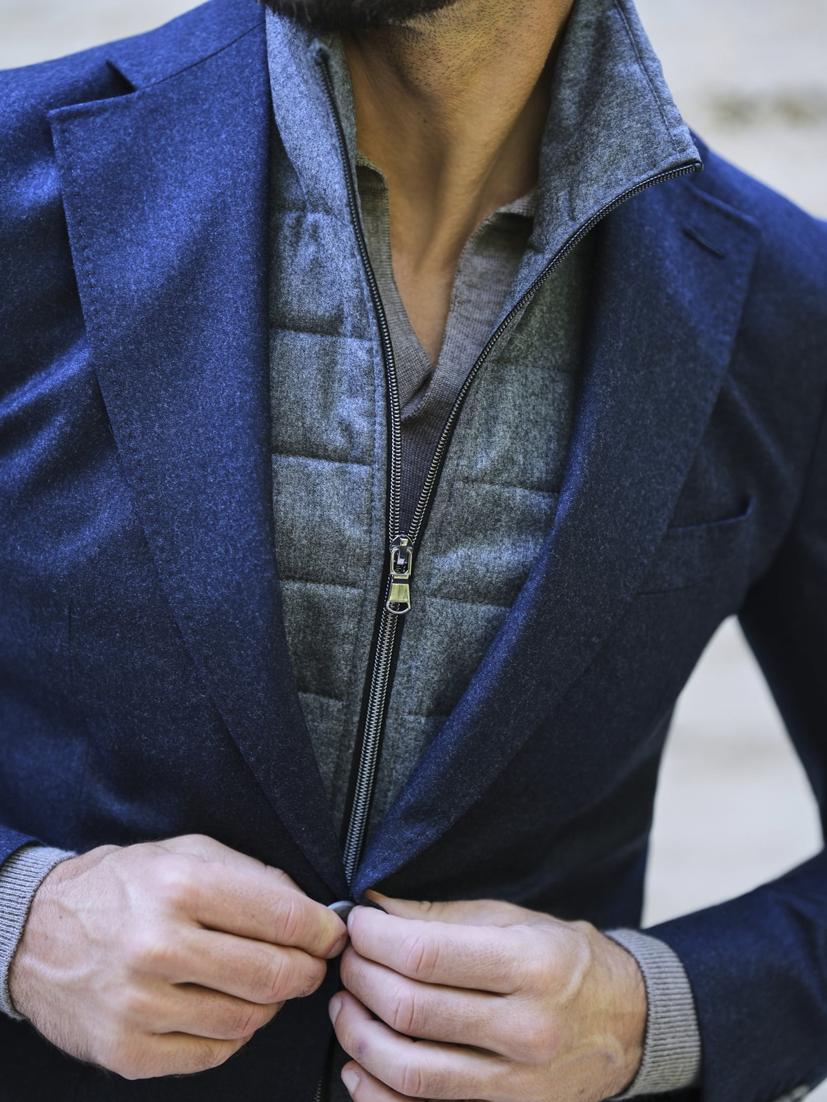 Consiglieri: quilted texture and zip of a grey gilet beneath a blue lapel