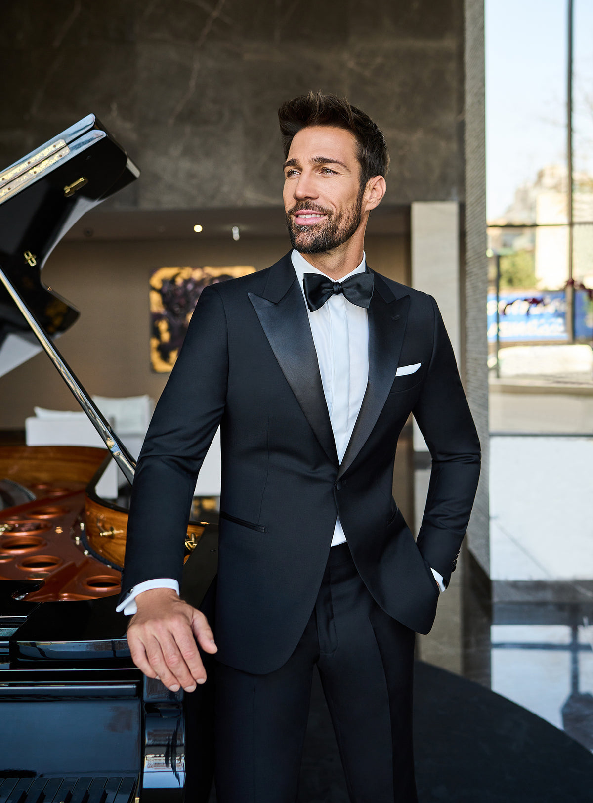 Consiglieri: black shawl-collar tuxedo with a white shirt and bow tie beside a piano