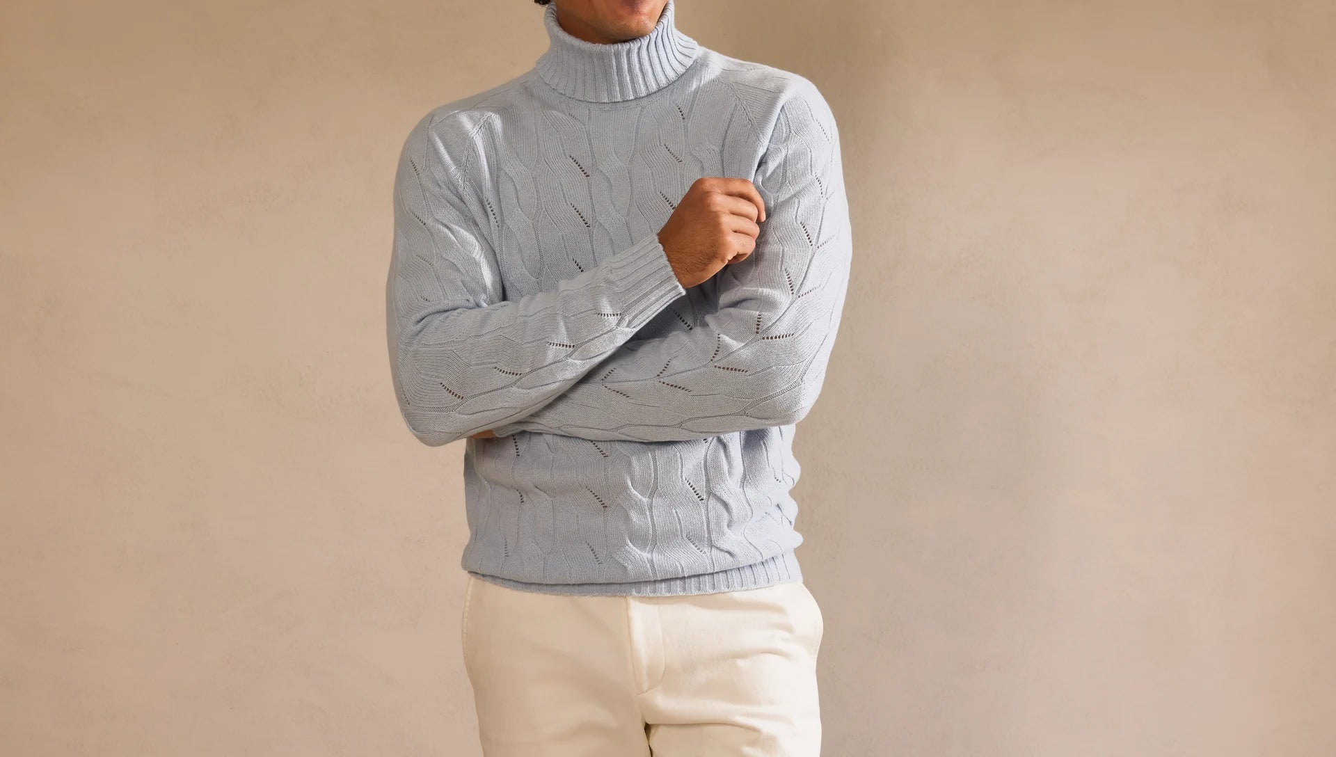 Pale blue cable-knit rollneck worn with ivory trousers