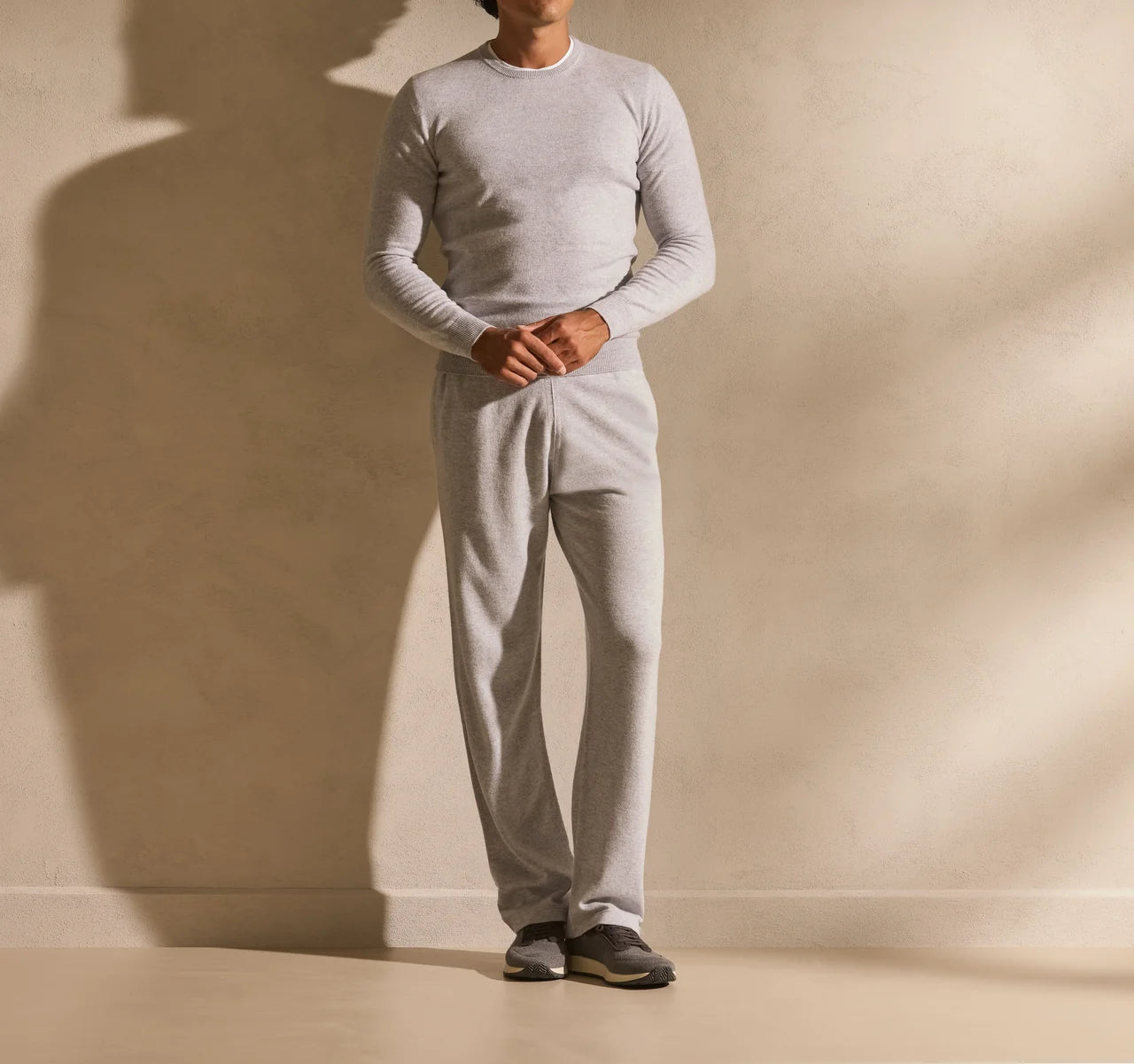 Tonal grey outfit with a plain knit, relaxed trousers and grey footwear.