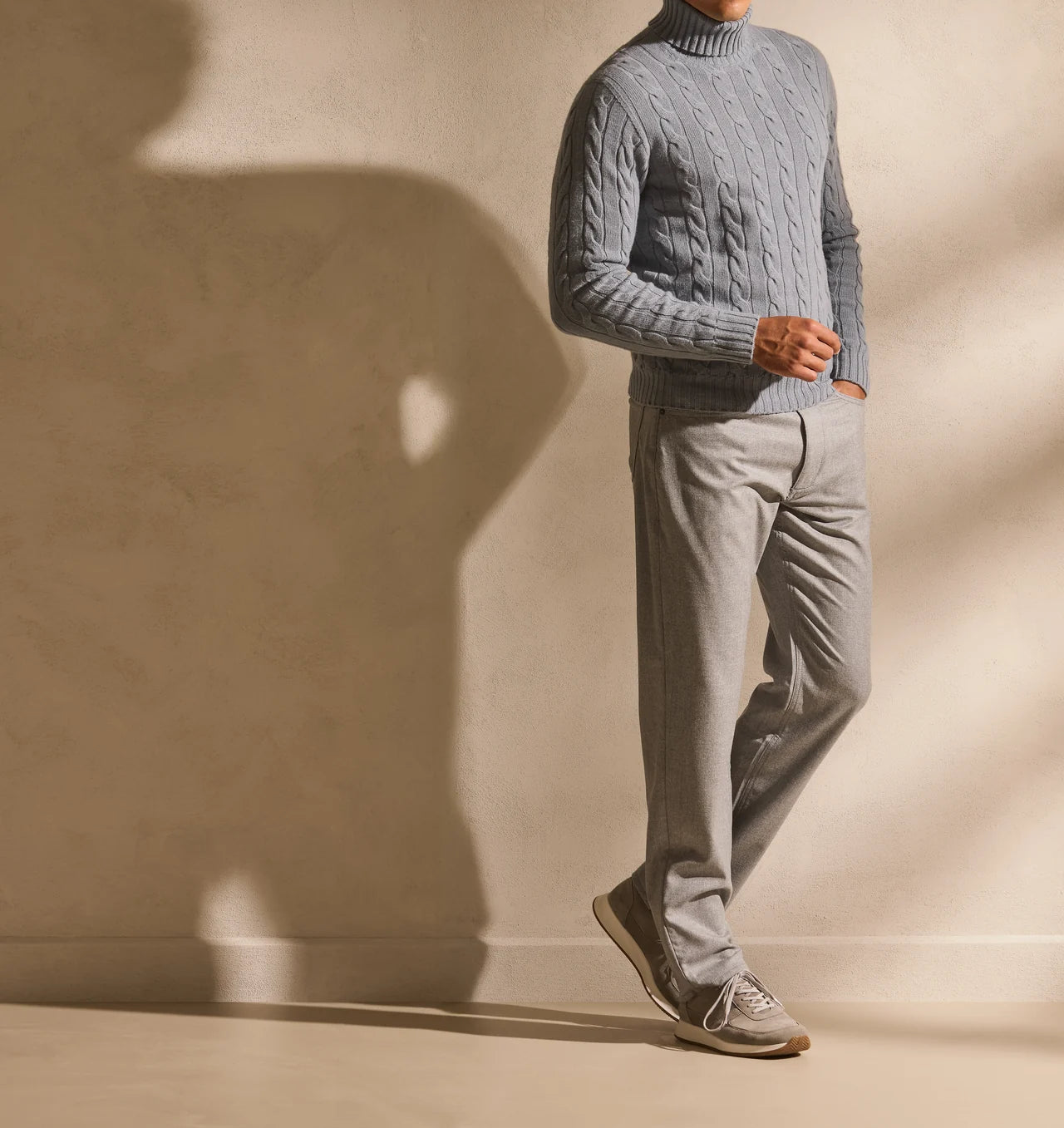 Steel-blue cable-knit rollneck with grey trousers and tonal footwear.