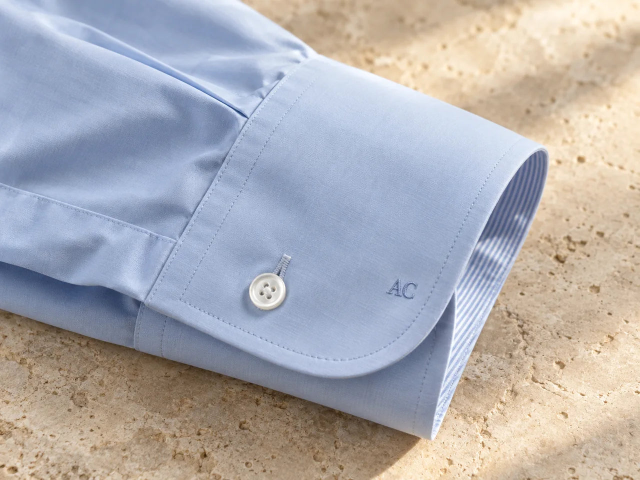A discreet embroidered monogram on a pale blue shirt cuff