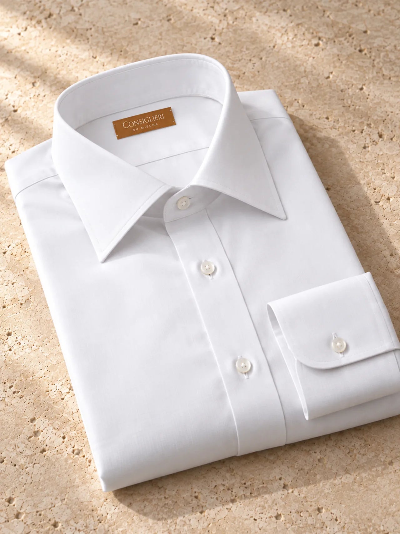 Folded classic white shirt, with the collar and cuff in view.