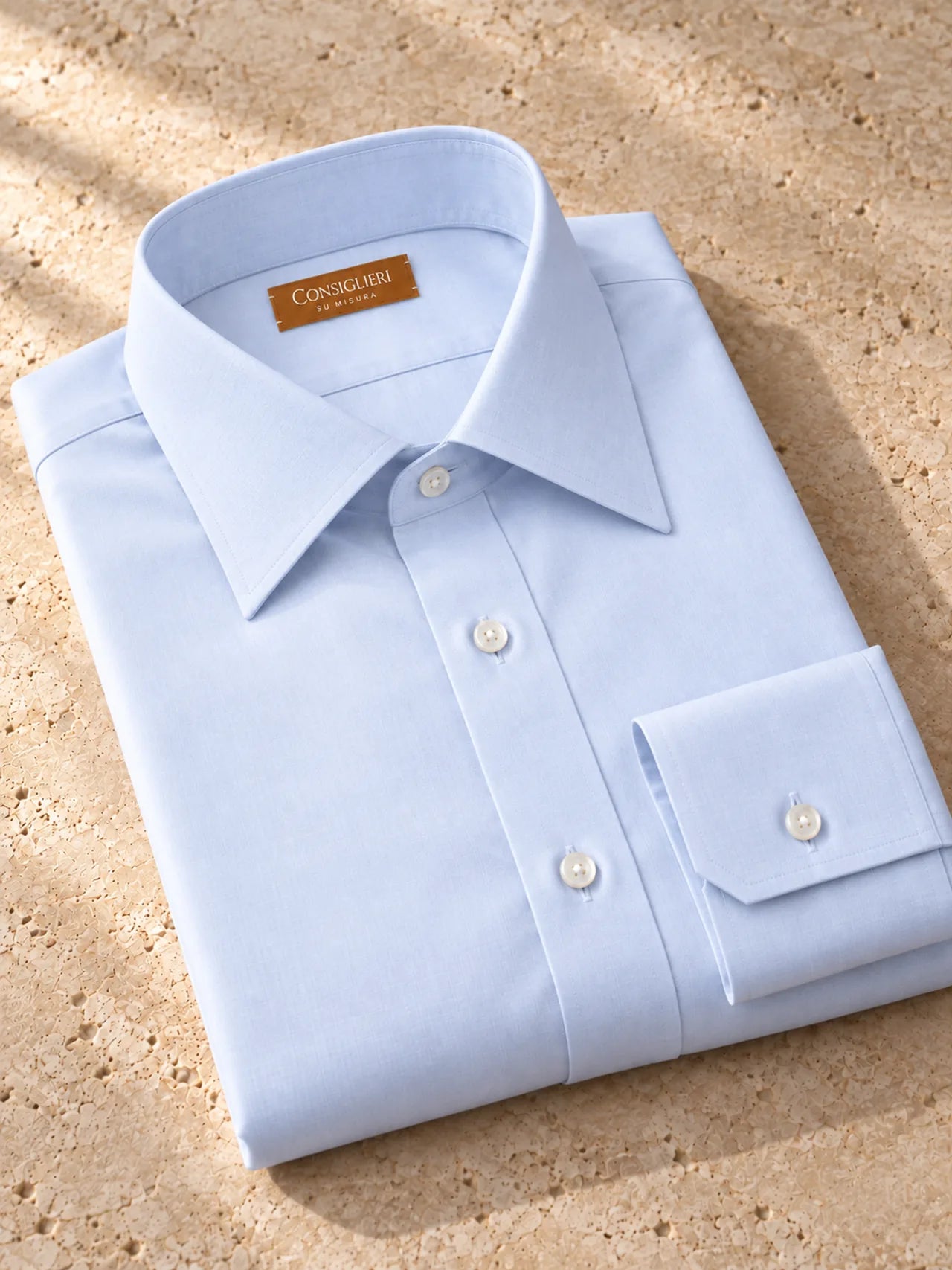 Folded essential light blue shirt, with the collar and cuff in view.