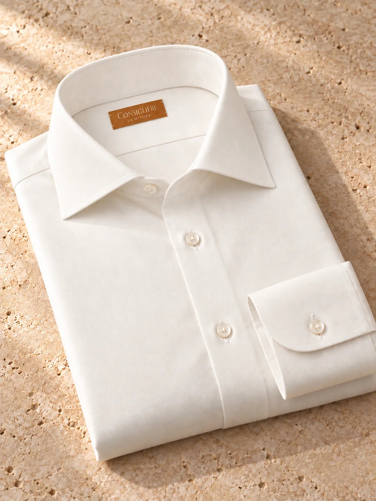 Folded quiet ivory shirt, with the collar and cuff in view.