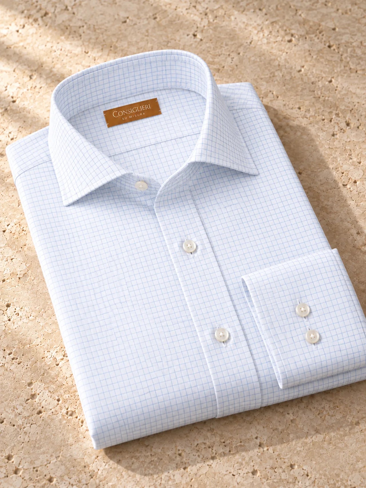 Folded fine check shirt, with the collar and cuff in view.