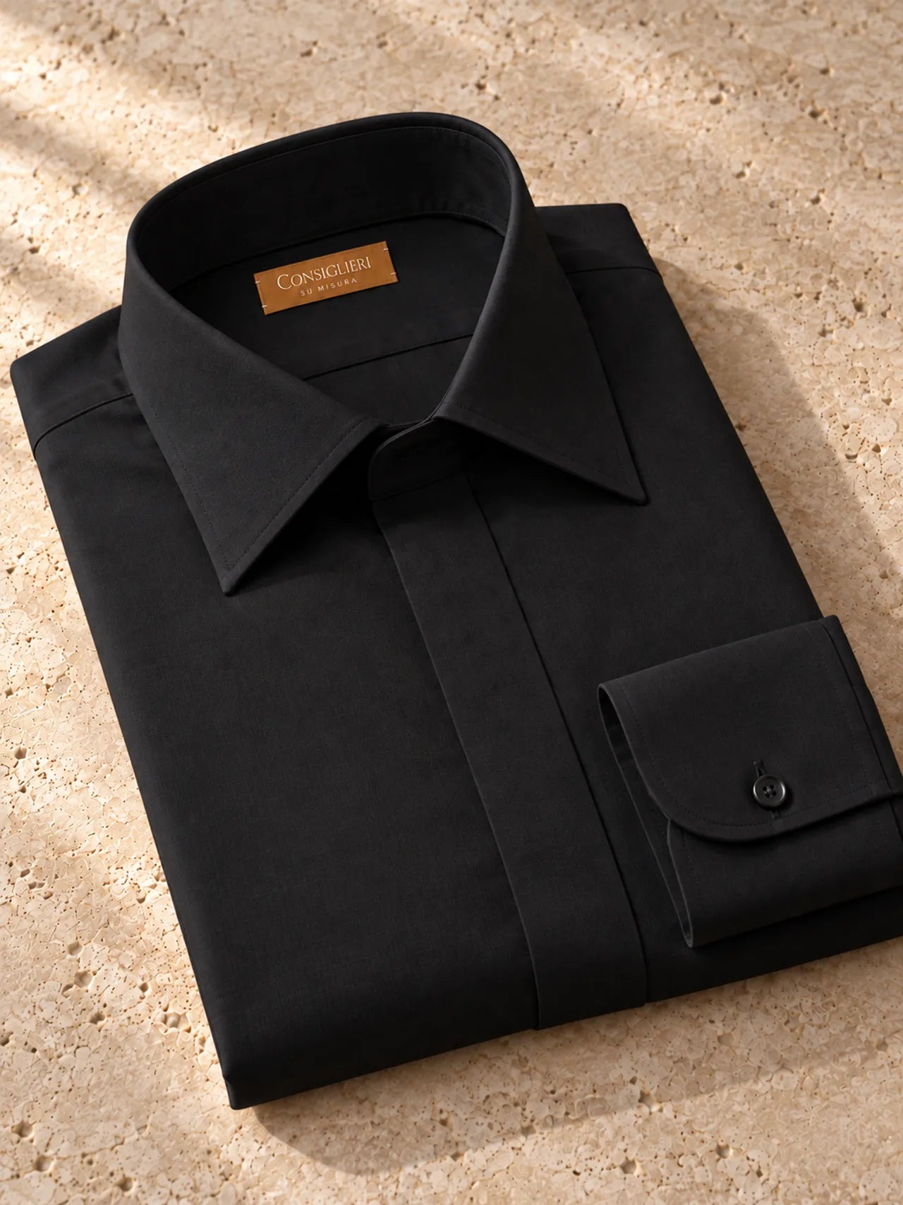 Folded deep black shirt, with the collar and cuff in view.
