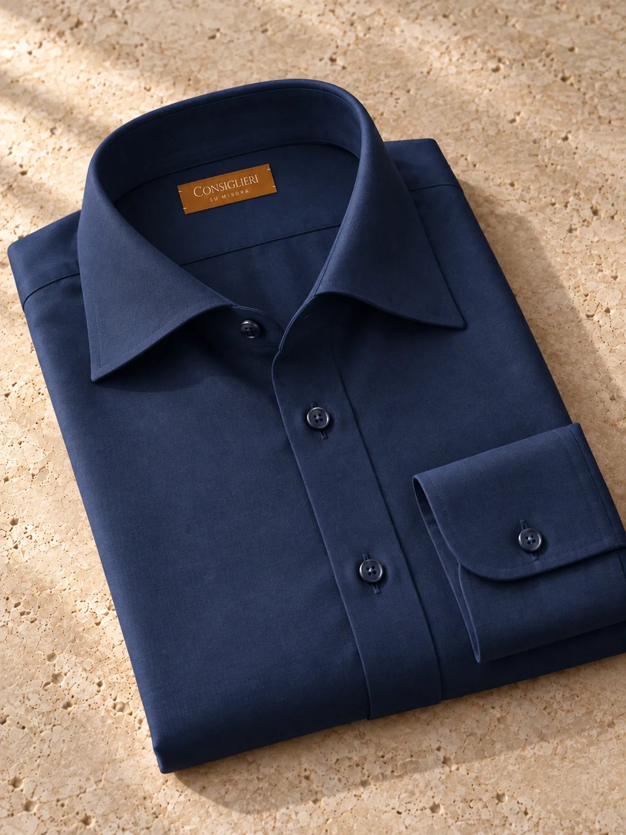 Folded deep blue shirt, with the collar and cuff in view.