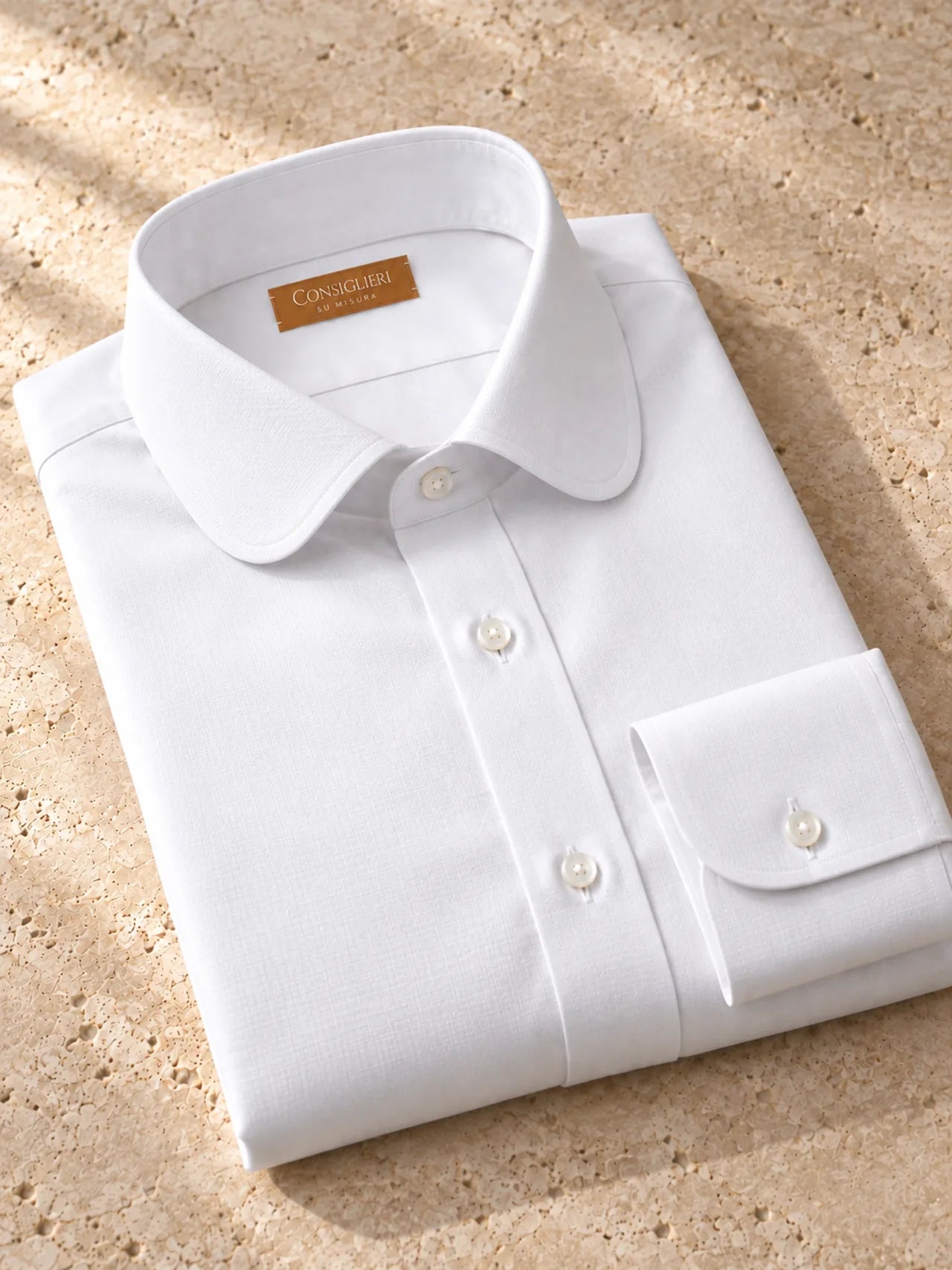 Folded contoured white shirt, with the collar and cuff in view.